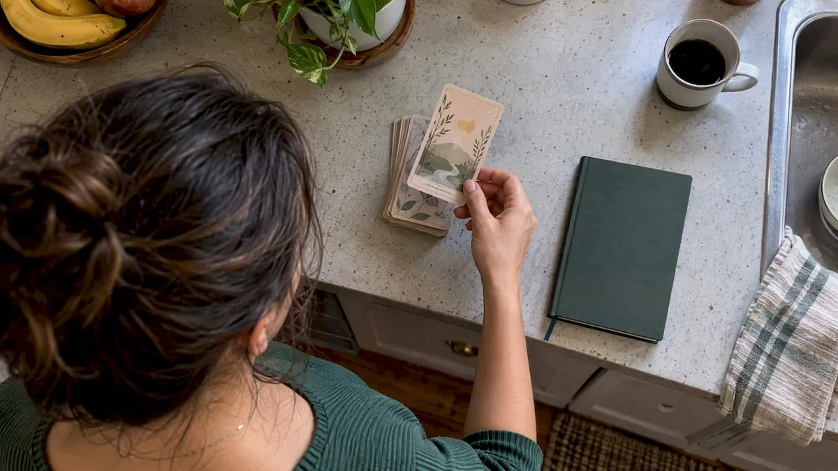 Hand drawing an oracle card beside a journal